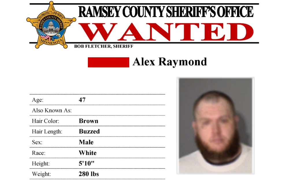 A screenshot of a wanted poster from the Ramsey County Sheriff's Office, displaying a badge, the title "WANTED" in bold red, and the personal details and mugshot of a male individual, including age, alternative names, physical characteristics, and weight.